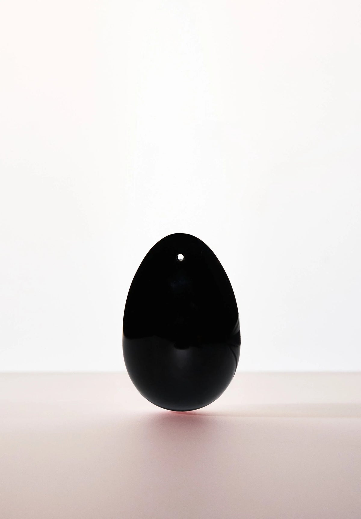 Black Obsidian yoni egg with drilled hole, from Anastasia's Bedroom Lingerie, showcasing smooth, polished gemstone for intimate wellness.